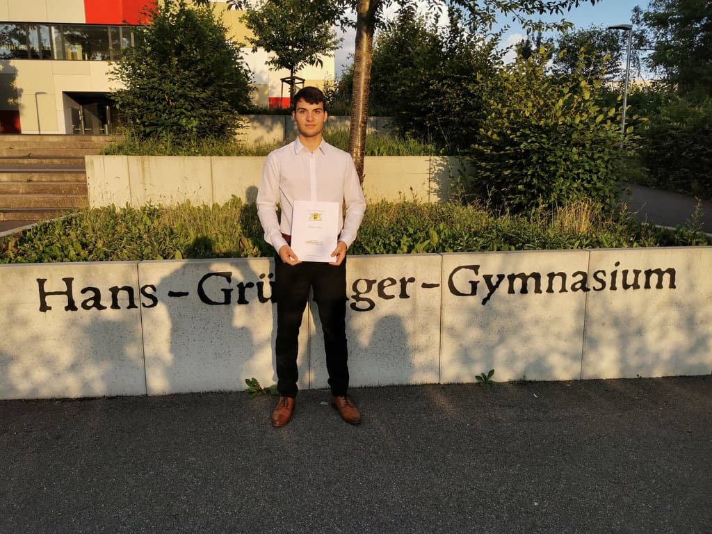 Lukas standing in front of the Hans-Grüninger-Gymnasium sign